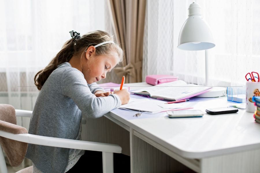 Elementary School girl takes responsibility for doing her own homework.