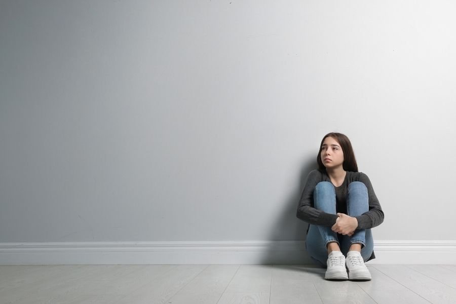 Girl sitting alone after being excluded by her mean friends